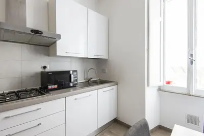 a kitchen with white cabinets and a sink and a microwave at Vatican Cosy Apartment in Rome