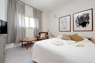 a white bedroom with a large bed and a table at Monte del Gallo Apartment for groups in Rome