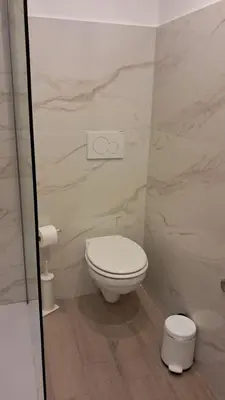 a bathroom with a white toilet and marble walls at Domus Turno by Local Domus in Rome