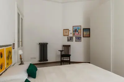 a white bedroom with a bed and a chair at Casa Dandolo - Pretty Homes in Rome
