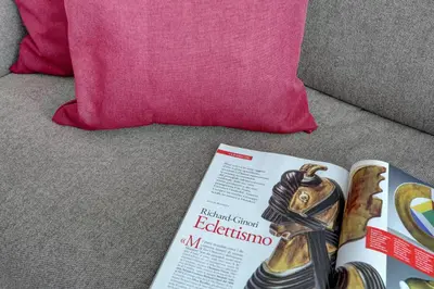 a magazine sitting on a couch next to a pink pillow at Vatican Apt Doria 64 - Home and More in Rome