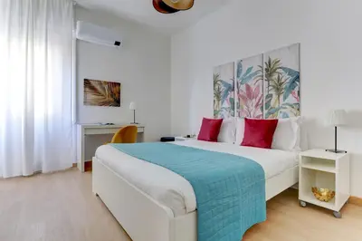 a white bedroom with a large bed with red pillows at Vatican Apt Doria 64 - Home and More in Rome