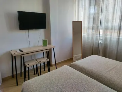 a room with two beds and a desk with a television at Ponentino B&B in Rome