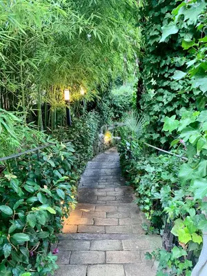a stone path through a garden with plants at Giardino dei Giganti, 5 minute walk to the subway B in Rome