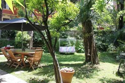 a table and chairs with an umbrella in a garden at Giardino dei Giganti, 5 minute walk to the subway B in Rome