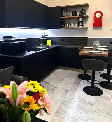 a kitchen with black cabinets and a table with flowers at Via Veneto Luxury House in Rome