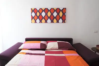 a bed with colorful pillows and a painting on the wall at Eurialo Roma Design Apartment - MyItalianStay in Rome