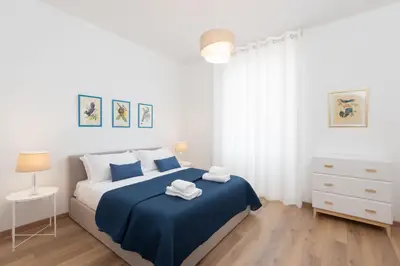 a white bedroom with a blue bed with towels on it at 25 Penthouse Porta Pia in Rome