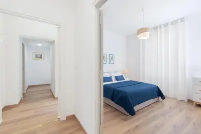 a white bedroom with a blue bed and a mirror at 25 Penthouse Porta Pia in Rome