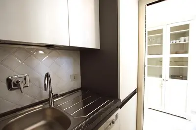 a kitchen with a stainless steel sink and white cabinets at Testaccio View Holiday House in Rome