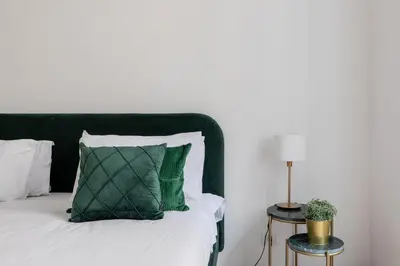 a bed with a green pillow and a side table at iFlat Comfortable Apartment next to the Vatican in Rome