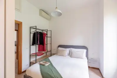 a bedroom with a white bed and a rack of clothes at iFlat Comfortable Apartment next to the Vatican in Rome
