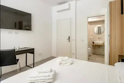 a white bedroom with a desk and a bed with towels at Roma private rooms Vatican City in Rome