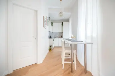 a white kitchen with a table and a stool at Appartamento San Giovanni fino a 6 persone in Rome
