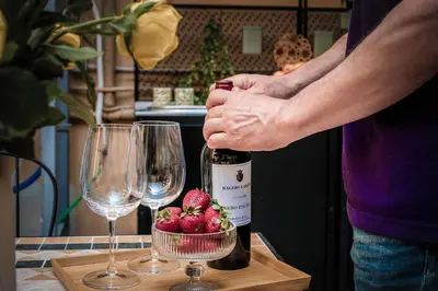 a person opening a bottle of wine next to two glasses at Appartamento San Giovanni fino a 6 persone in Rome