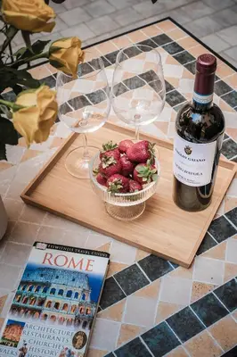 a table with two glasses and a bottle of wine and a bowl of strawberries at Appartamento San Giovanni fino a 6 persone in Rome