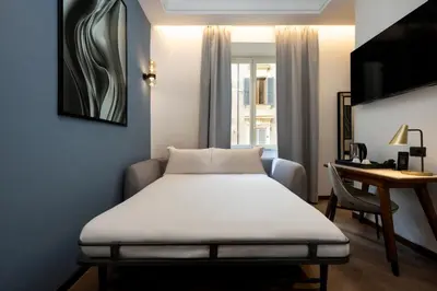 a bed in a room with a desk and a table at Boutique Hotel Piedra Rome City Centre in Rome