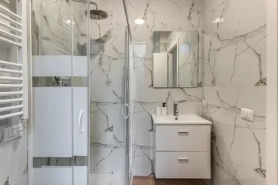 a white bathroom with a shower and a sink at Orazio's Charming Apartment in Rome