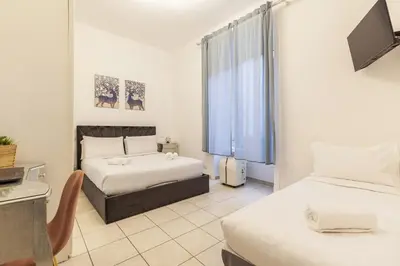 a hotel room with two beds and a television at Hostly-Michelangelo Cloister Suite-Center of Rome in Rome