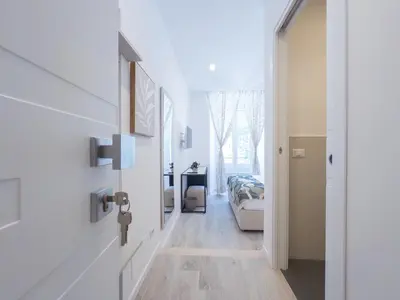 a hallway with white walls and wooden floors and a clock on the wall at White Ottaviano in Rome