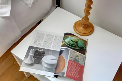 a magazine on a white table with a lamp at Colosseo Family Art 3BDR - Home and More in Rome