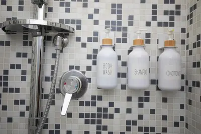 a shower with four bottles on a tiled wall at Amores Roma Apartment in Rome
