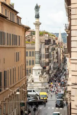 a busy city street with a large statue in the middle of a street at Roma Centro Storico Luxury - Piazza di Spagna in Rome