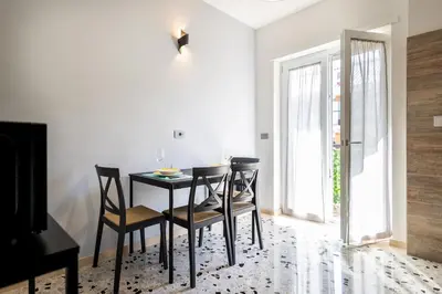 a dining room with a table and chairs and a window at Marconi white flower house in Rome