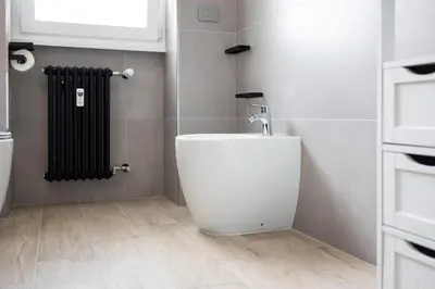 a white toilet in a bathroom with a radiator at Marconi white flower house in Rome