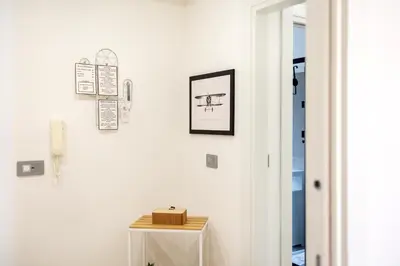 a white hallway with a table and a picture on the wall at Marconi white flower house in Rome