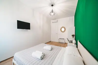 a bedroom with a white bed and a green wall at Tibur Domus B&B in Rome