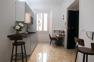 a kitchen with white cabinets and a table and chairs at Vatican 23 Museum Suites in Rome