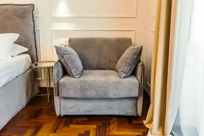 a chair with two pillows sitting next to a bed at Augusto Imperatore Suite in Rome