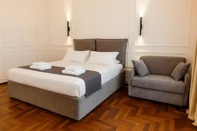 a bedroom with a bed and a chair at Augusto Imperatore Suite in Rome