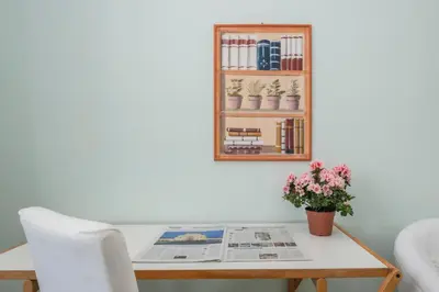 a table with a newspaper and a shelf with books at Vatican Zen House - Cale 05 in Rome
