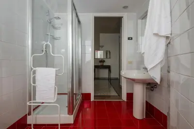 a bathroom with a shower and a sink and red floor at Vatican Zen House - Cale 05 in Rome
