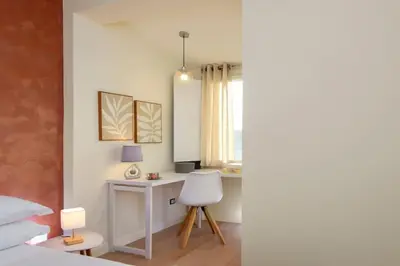 a bedroom with a bed and a desk with a chair at San Pietro Nausicaa Penthouse in Rome