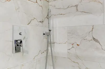 a shower in a bathroom with a marble wall at San Giovanni Cozy Apt - Home and More in Rome