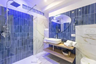 a blue tiled bathroom with a sink and a shower at Flowery Rainbow in Rome