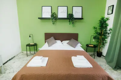a bedroom with a large bed with two chairs and plants at RHOME SUITE VATICAN APTS in Rome
