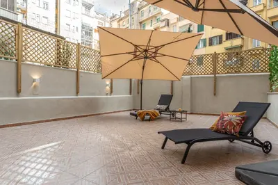 a patio with two chairs and a large umbrella at YCH-Ambra Apartments a San Giovanni in Rome