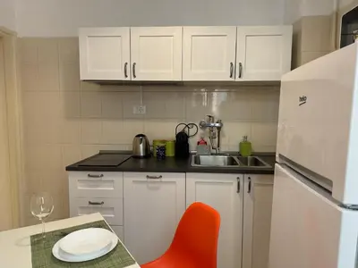a kitchen with white cabinets and a red chair and a table at The Best Rent - Spacious one-bedroom apartment near Colosseum in Rome