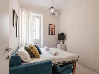 a bedroom with a bed and a blue couch at The Best Rent - Spacious one-bedroom apartment near Colosseum in Rome