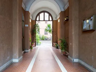an empty hallway in a building with a window and plants at The Best Rent - Spacious one-bedroom apartment near Colosseum in Rome