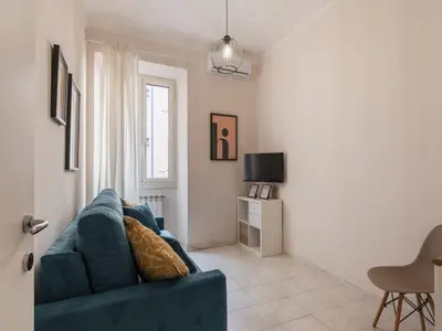 a living room with a blue couch and a tv at The Best Rent - Spacious one-bedroom apartment near Colosseum in Rome