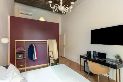 a bedroom with a bed and a desk and a tv at Residenza Il Vicolo by Hili in Rome
