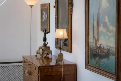 a lamp on a dresser in a room with paintings at Tre Lune Penthouse by Rental in Roma in Rome