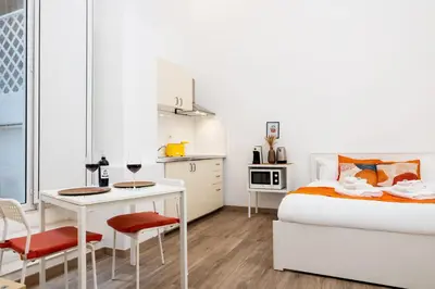 a white bedroom with a bed and a table and chairs at Archetto by the Vatican in Rome