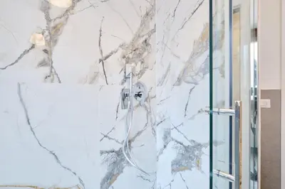 a shower in a bathroom with a marble wall at Monteverde - Vaticano - Esperienza Romana 1BDR by Hôtea in Rome