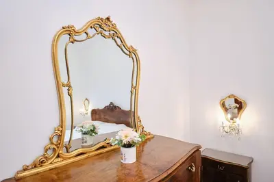 a mirror on top of a wooden dresser with flowers at Monteverde - Vaticano - Esperienza Romana 1BDR by Hôtea in Rome